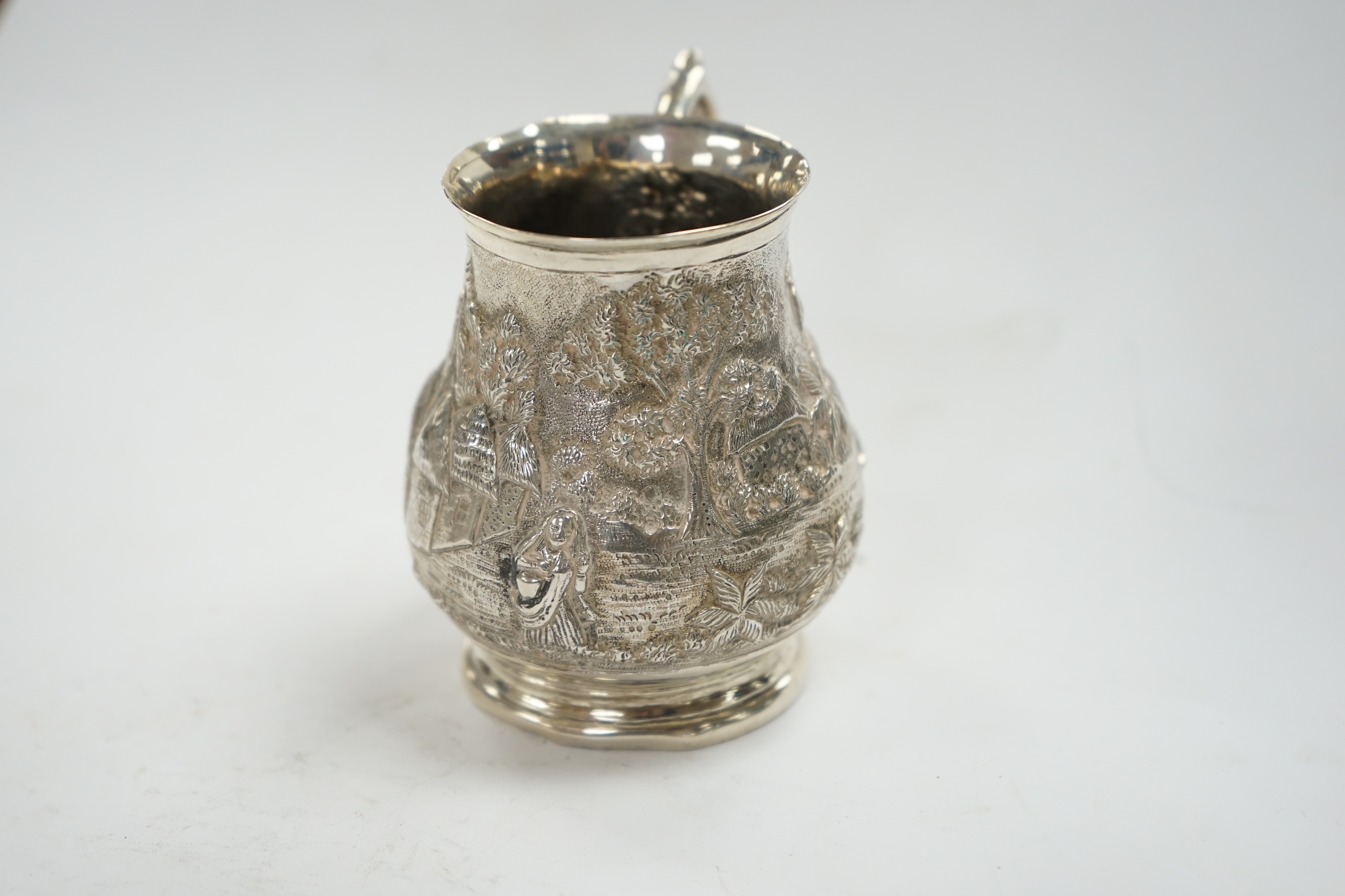 An Indian embossed white metal baluster mug, height 77mm, 94 grams. Condition - poor to fair